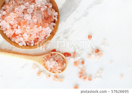 top view of himalayan pink rock salt in wooden bowl and spoon on white marble table. top view of himalayan pink rock salt in wooden bowl and spoon on white marble table. 57626695