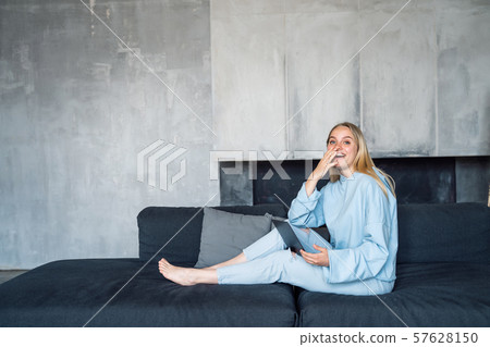 Image of happy woman using silver laptop while sitting on sofa 57628150