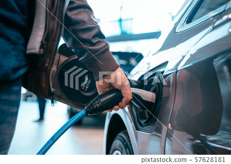 Human hand is holding Electric Car Charging connect to Electric car Human hand is holding Electric Car Charging connect to Electric car 57628181