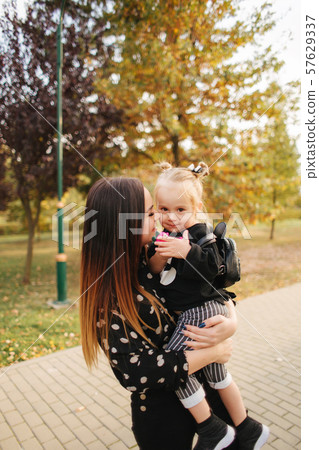 Mother and little daughter walking in autumn weather. Stylish little daughter and her beautiful 57629337