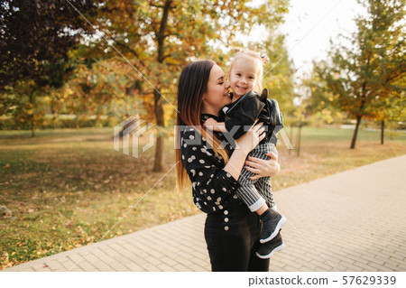 Mother and little daughter walking in autumn weather. Stylish little daughter and her beautiful Mother and little daughter walking in autumn weather. Stylish little daughter and her beautiful 57629339