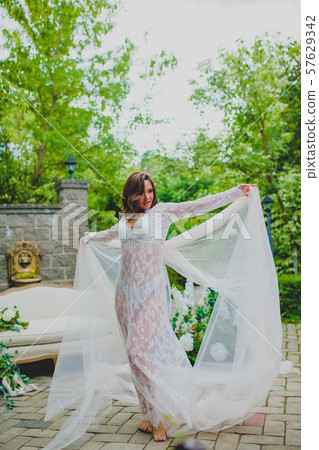 Seductive young bride in white negligee dancing with big piece of white fabric Seductive young bride in white negligee dancing with big piece of white fabric 57629342