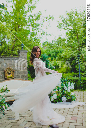 Seductive young bride in white negligee posing with big piece of white fabric 57629368