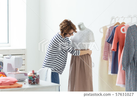 Fashion designer, seamstress and Small-Sized Enterprises concept - woman seamstress decorates a 57631027
