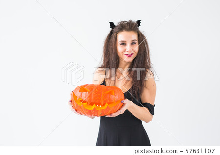 Halloween and masquerade concept - Beautiful young woman posing with Pumpkin Jack-o'-lantern Halloween and masquerade concept - Beautiful young woman posing with Pumpkin Jack-o'-lantern 57631107