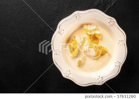 Italian tortellini with a cream sauce, shot from the top on a black background with a place for text 57631260