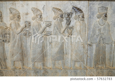 A bas-relief depiction of tribute bearer men carry present for the king at Apadana, Persepolis. Shiraz, Iran. 57632783