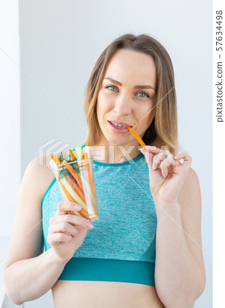 Diet concept - Healthy lifestyle woman eating vegetables smiling happy indoors. Young female eating 57634498