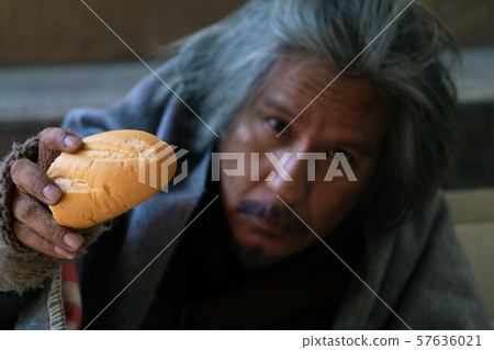 Homeless man is sitting down on staircase in town.He is Show bread.He is very unhappy.focus is bread .poverty,despair, Photo Sympathetic and hope concept. Homeless man is sitting down on staircase in town.He is Show bread.He is very unhappy.focus is bread .poverty,despair, Photo Sympathetic and hope concept. 57636021