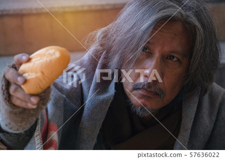 Homeless man is sitting down on staircase in town.He is Show bread.He is very unhappy.focus is bread .poverty,despair, Photo Sympathetic and hope concept. 57636022