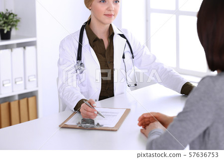 Young woman doctor and patient at medical examination in hospital office. Khaki colored blouse of 57636753
