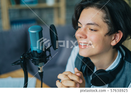 Emotional kid speaking in microphone in studio recording podcast gesturing 57638925