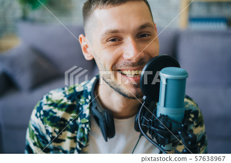 Portrait of joyful guy talking in microphone in recording studio smiling 57638967