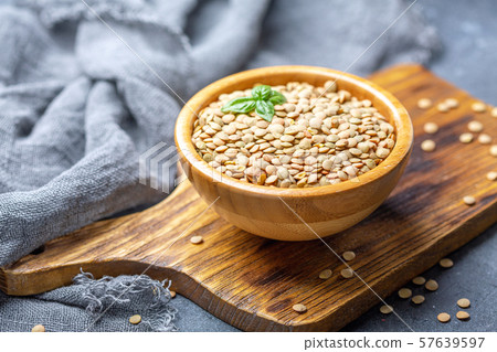 Dry brown lentils in a wooden bowl. Dry brown lentils in a wooden bowl. 57639597