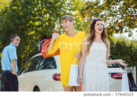 Women with shopping bags getting out of taxi Women with shopping bags getting out of taxi 57640325