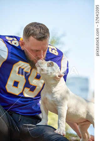 American football player with a dog posing on camera in a park. Copy space, sports banner. Concept 57641095