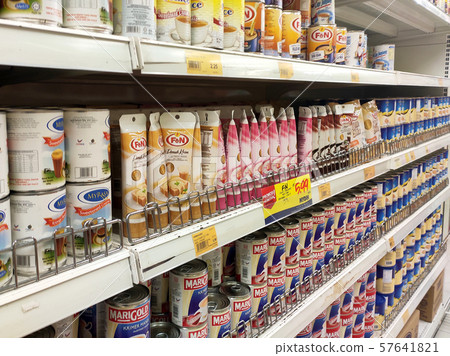 Sweetened creamer and evaporated creamer in cans displayed for sale on the rack inside the supermarket. 57641821