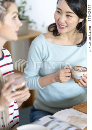 International Asian woman planning a trip with a foreign friend in a cafe 57642435