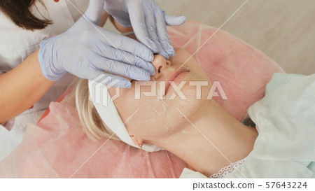 Applying cream on the face of the girl in the salon. Cleaning and care of the face. Applying cream on the face of the girl in the salon. Cleaning and care of the face. 57643224