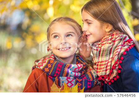 Two cute smiling 8 years old girls chatting in a park on a sunny autumn day. Two cute smiling 8 years old girls chatting in a park on a sunny autumn day. 57646456