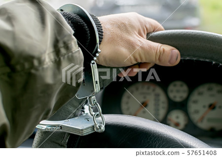 Car driver hand handcuffed to steering wheel, arrest, driving ban Car driver hand handcuffed to steering wheel, arrest, driving ban 57651408