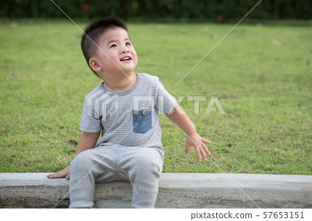 Portrait of smile asian baby boy sitting on the edge of the footpath in park. Portrait of smile asian baby boy sitting on the edge of the footpath in park. 57653151