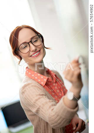 Smiling teacher explaining material near blackboard 57654902