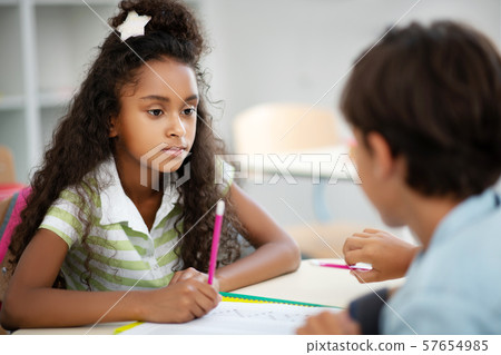 Cute dark-eyed girl listening to classmate while discussing test 57654985