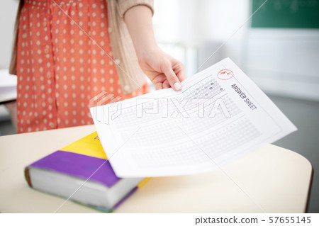 Teacher wearing spotted dress holding answer sheet for tests 57655145