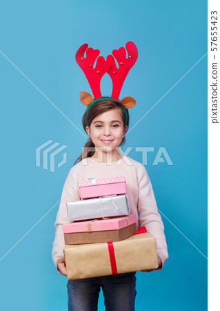 Smiling funny child with reindeer antlers holding Christmas gifts in hand. Christmas concept. Smiling funny child with reindeer antlers holding Christmas gifts in hand. Christmas concept. 57655423