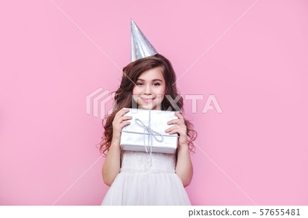 Portrait of cute little girl with gift box on pink background. Birthday party 57655481