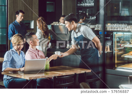 Handsome man being served a cup of coffee at the cafe Handsome man being served a cup of coffee at the cafe 57656887