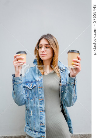 Blonde girl with paper cups of coffee on grey Blonde girl with paper cups of coffee on grey 57659448