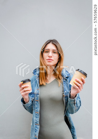 Blonde girl with paper cups of coffee on grey Blonde girl with paper cups of coffee on grey 57659629