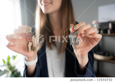 Young pretty woman smiles. House key in womans hands. . Modern light lobby interior. Real estate Young pretty woman smiles. House key in womans hands. . Modern light lobby interior. Real estate 57659750