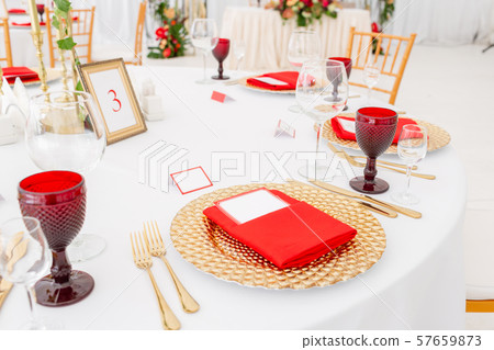 Table setting red napkins and glasses, gold plates. Interior of a wedding tent decoration ready for 57659873