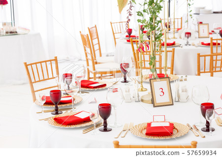Table setting red napkins and glasses, gold plates. Interior of a wedding tent decoration ready for 57659934