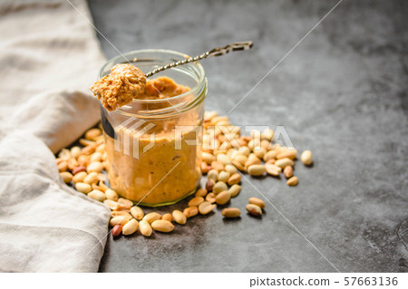 Fresh peanut spread in jar and spoon and scattered Fresh peanut spread in jar and spoon and scattered 57663136