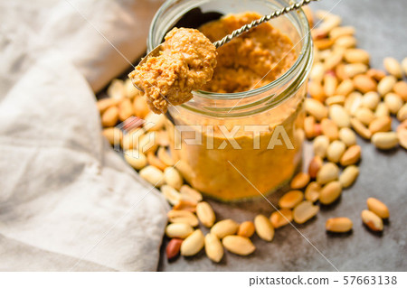 Fresh peanut spread in jar and spoon and scattered 57663138