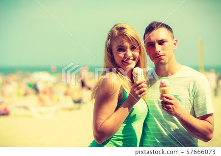 Man and woman eating ice cream on beach Man and woman eating ice cream on beach 57666073