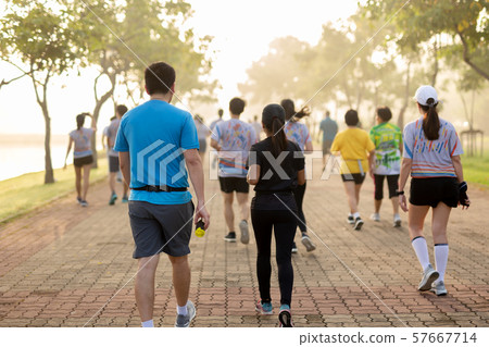 Man holding energy drink in a group of people exercise in the park in morning. 57667714