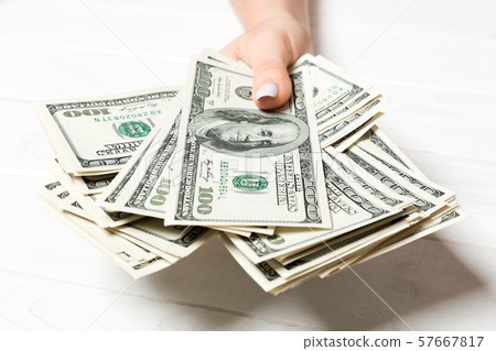 Female hand holding a bundle of one hundred dollar 57667817
