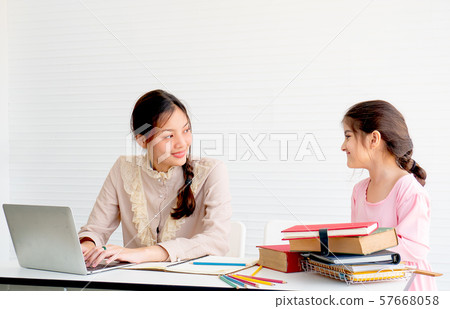 Beauty teen girl is working with laptop and look to her sister with smile Beauty teen girl is working with laptop and look to her sister with smile 57668058