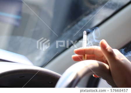 A man who smokes in the car while driving. 57668457