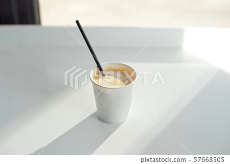 One simple takeaway paper cups on a white wooden table with a black paper tube. 57668505