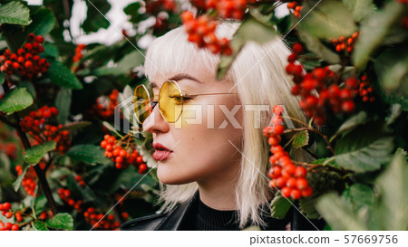 Portrait of young woman standing by rowan tree Portrait of young woman standing by rowan tree 57669756