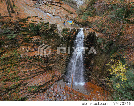 man with woman holding ukrainian flag on the top of the waterfall man with woman holding ukrainian flag on the top of the waterfall 57670746