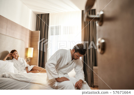 I'm not sure... Couple relaxing in hotel room wearing robes 57671664
