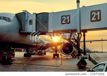 Modern passenger airplane parked to terminal building gate at airside apron of airport with close up Modern passenger airplane parked to terminal building gate at airside apron of airport with close up 57671988
