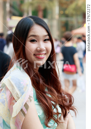 Beautiful Asian woman smiling with outdoor scene. 57672272